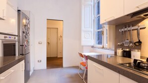 Une cuisine moderne dotée d’appareils électroménagers en acier inoxydable, d’une fenêtre avec stores et d’un plan de travail agrémenté d’ustensiles de cuisine.