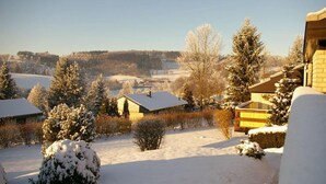 Un paysage enneigé avec des maisons, des arbres et un ciel dégagé.