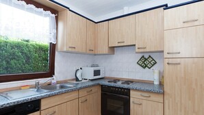 Une cuisine moderne dotée de meubles en bois, d’un lave-vaisselle, d’une cuisinière et d’un four à micro-ondes.