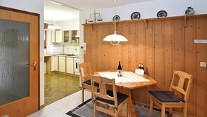 A dining area with a wooden table, four chairs, a wine bottle, and a wine glass. - Ferienwohnung in Schiltach (Schiltach)