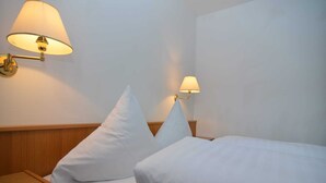A hotel room with two beds, each with white linens and pillows, and two wall-mounted lamps providing soft lighting. - Wohnung in Rotthalmünster mit Balkon (Rotthalmünster)