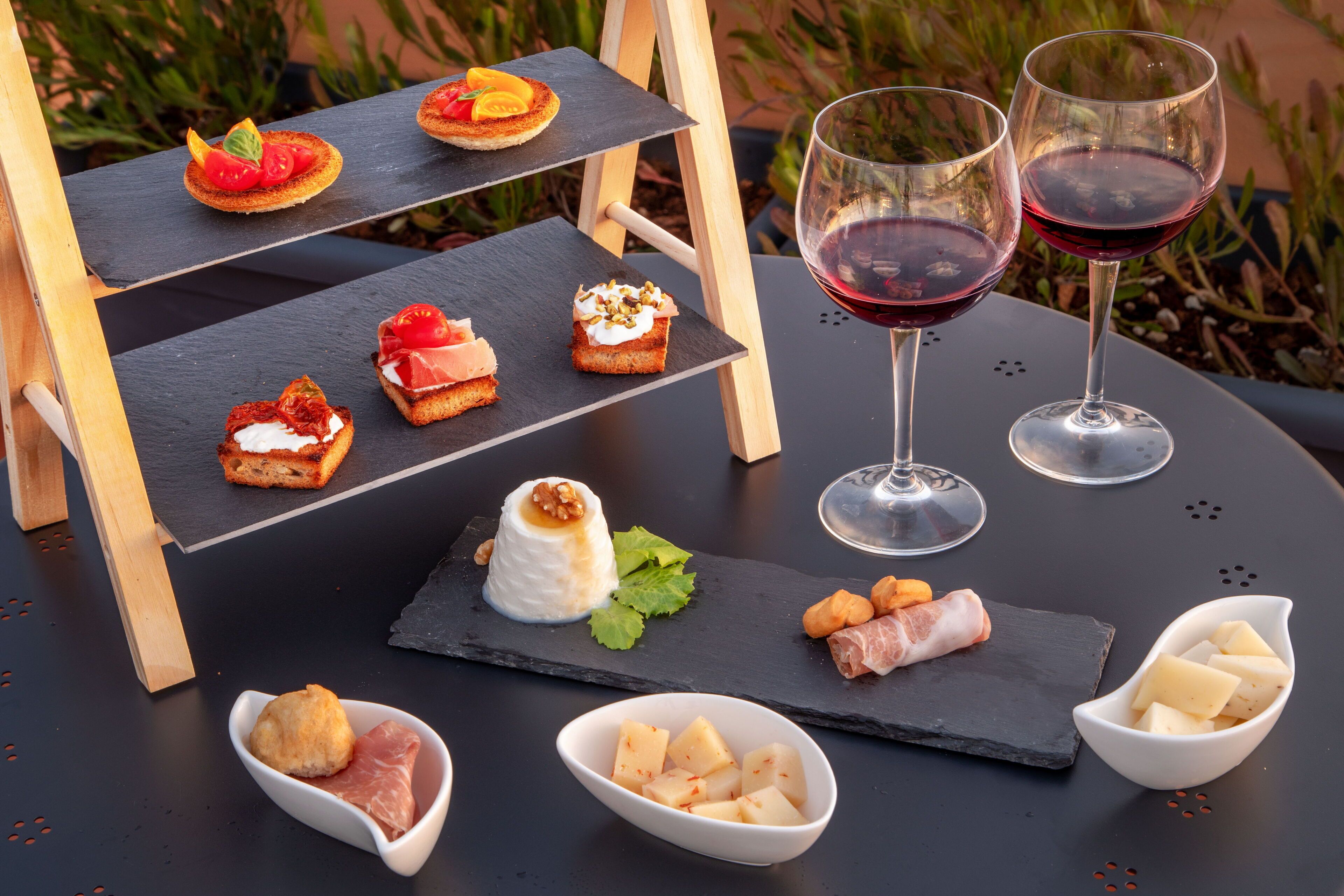 Una mesa con diferentes alimentos y dos copas de vino tinto.
