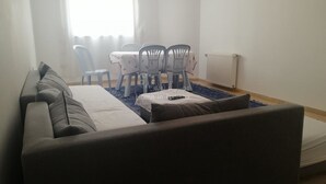 Ett modernt vardagsrum med en grå soffa, ett matbord med stolar och ett element.