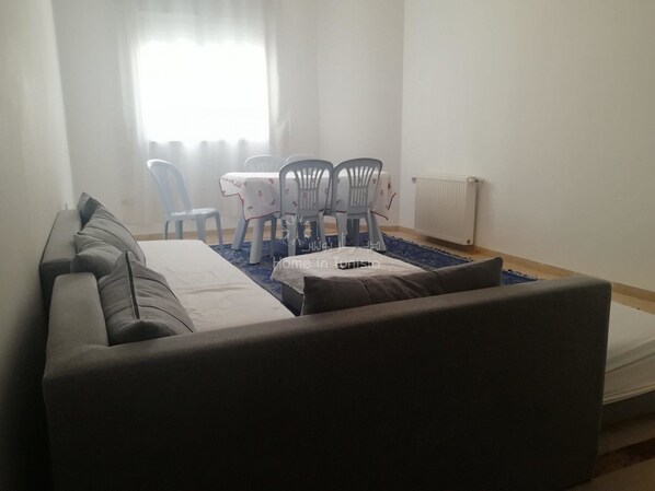 Ein modernes Wohnzimmer mit einem grauen Sofa, einem Esstisch mit Stühlen und einer Heizung.