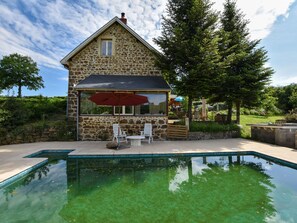 A stone building with a pool, outdoor seating, and a view of the surrounding greenery. - House near the truffle capital Aups (Virlet)