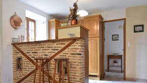 A kitchen with a brick island, wooden stools, a copper pot, and wooden cabinets. - Spacious holiday home with private pool (Uzech)