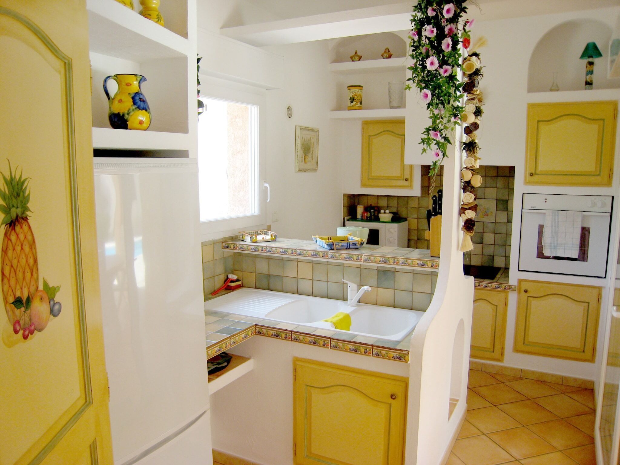 A kitchen with white cabinets, a refrigerator, a sink, and a window.