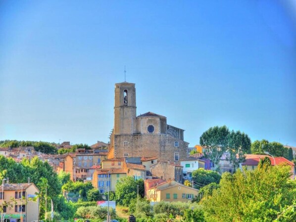 Una iglesia histórica con un campanario, rodeada de edificios coloridos y exuberante vegetación.