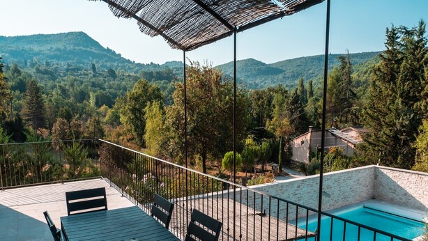Une terrasse sur le toit avec une piscine, des espaces de détente en plein air et une vue sur les collines environnantes.
