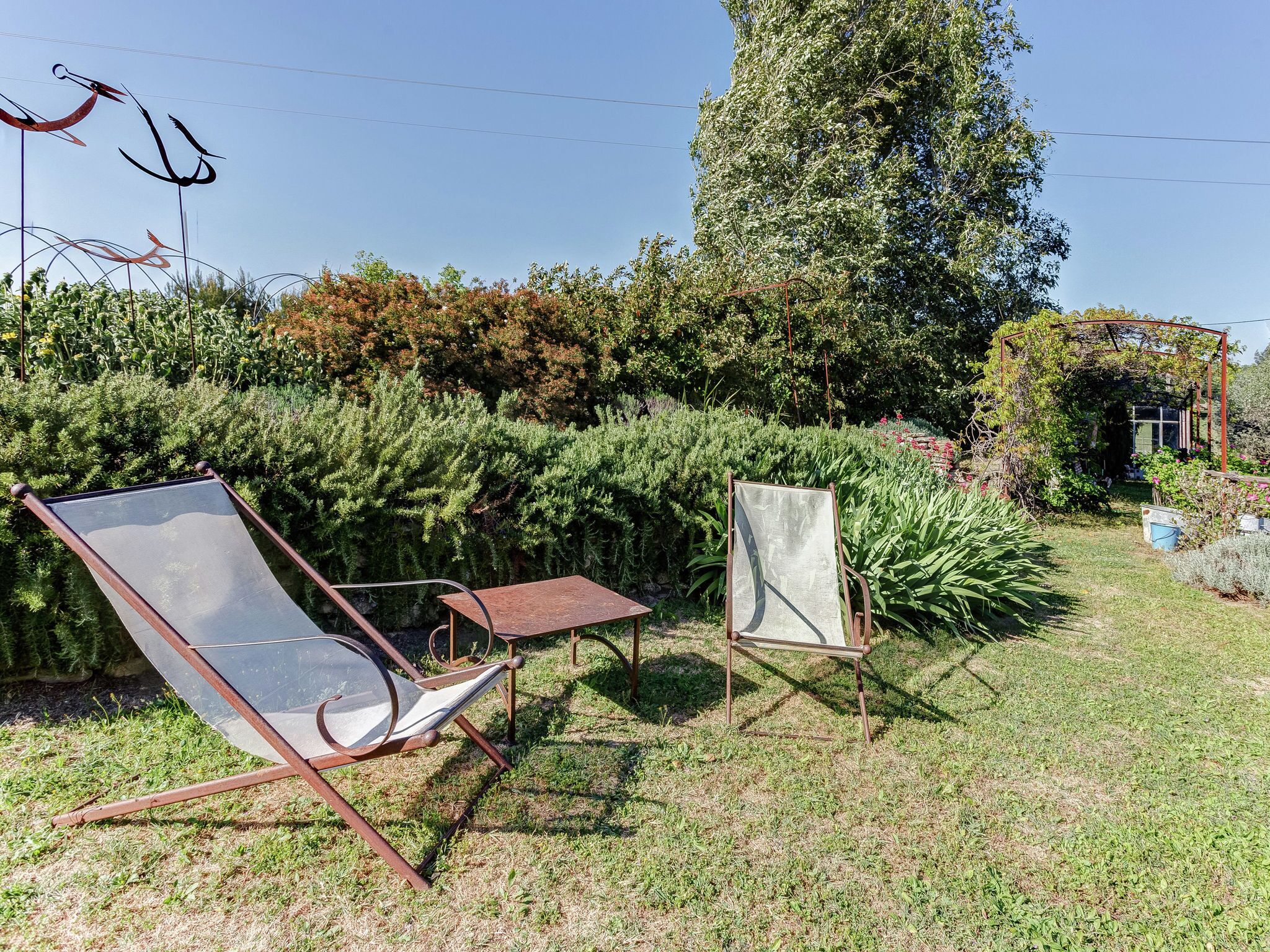 A garden with a metal chair, a small table, and a metal easel.