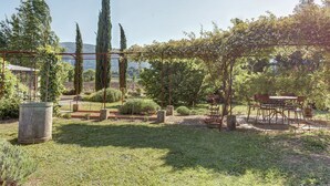 A garden with a pergola, seating area, and a stone planter. - Cottage in Oppède with Poolside Bliss (Oppède)