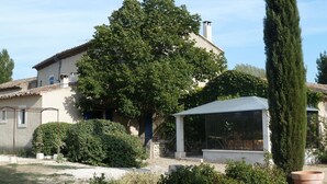 A house with a large tree, a covered patio, and a garden with potted plants. - Cottage in Oppède with Poolside Bliss (Oppède)