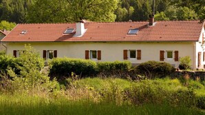 Ein zweistöckiges Haus mit roten Ziegeln, weißen Wänden und Holzläden.