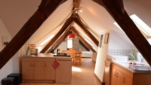 Ein gemütliches Schlafzimmer im Dachgeschoss mit Holzboden, einer kleinen Küchenzeile und einem Essbereich.
