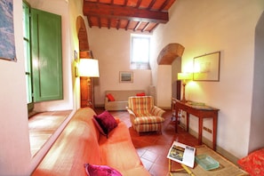 A cozy living room with a sofa, armchair, and a table with a lamp. - Belvilla by OYO Casa Bruciata (Rufina)