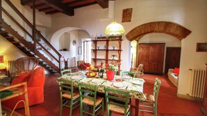 Un espace repas agrémenté d’un escalier en bois, d’une table de buffet et d’un luminaire suspendu.