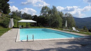 Une piscine rectangulaire surmontée d’un auvent blanc, avec des chaises longues disposées sur le côté.