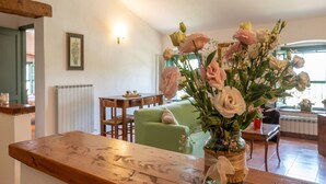 A cozy living room with a wooden table, a green sofa, and a vase of flowers. - Apartment near Pisa, Beaches (Collesalvetti (LI))