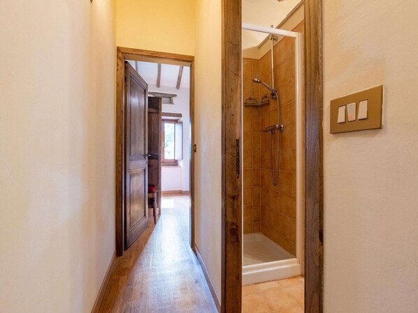 Un pasillo que conduce a un baño con ducha y puerta a otra habitación.