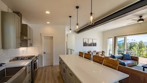 Una cocina moderna con una isla central, armarios de madera e iluminación colgante.