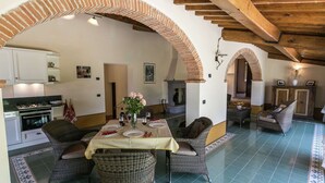 A dining area with a table set for four, surrounded by wicker chairs, under a vaulted ceiling with exposed beams.