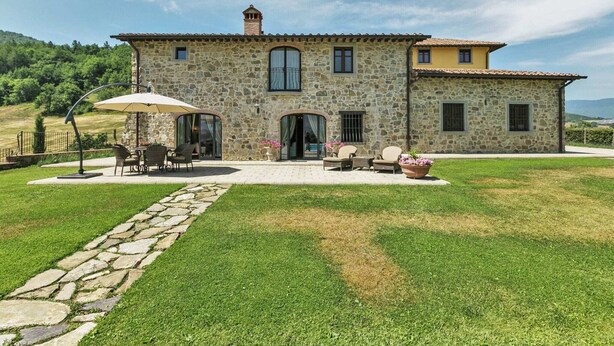 A stone house with a patio, outdoor seating, and a stone pathway.