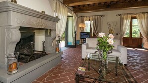 A living room with a fireplace, a glass coffee table, and a television in the background.