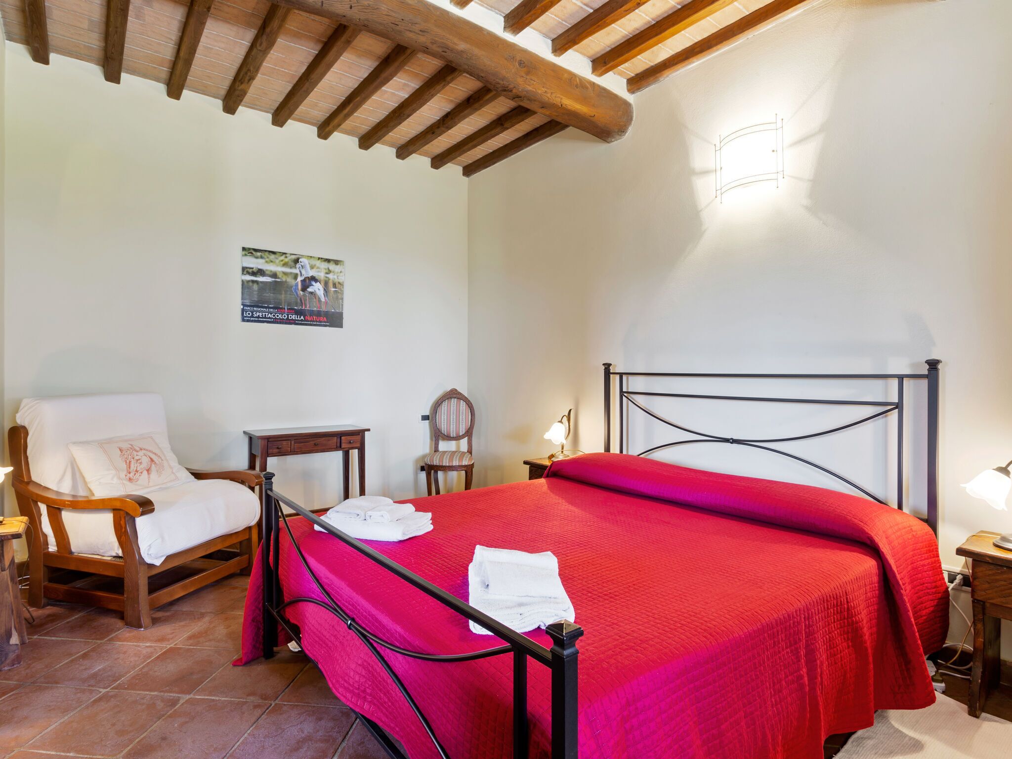 Un dormitorio con una cama, una silla, un escritorio y una lámpara.