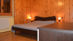 Camera da letto con pareti rivestite in legno, un letto, due lampade da comodino e un termosifone.