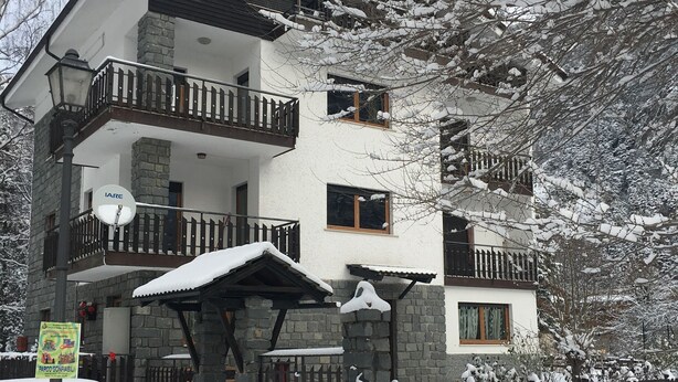 Un edificio a più piani con balconi, un'antenna parabolica e un tetto innevato.