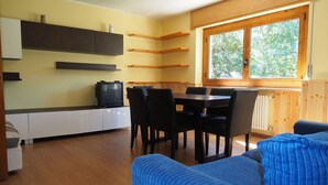 Una cucina moderna con mobili in legno, un tavolo da pranzo con sedie e un'ampia finestra vista alberi.