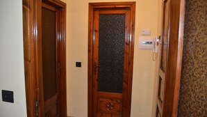 Un corridoio stretto con porte in legno, una delle quali presenta un pannello in vetro satinato.