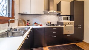 A modern kitchen with a stainless steel sink, a microwave, an oven, and black cabinets.