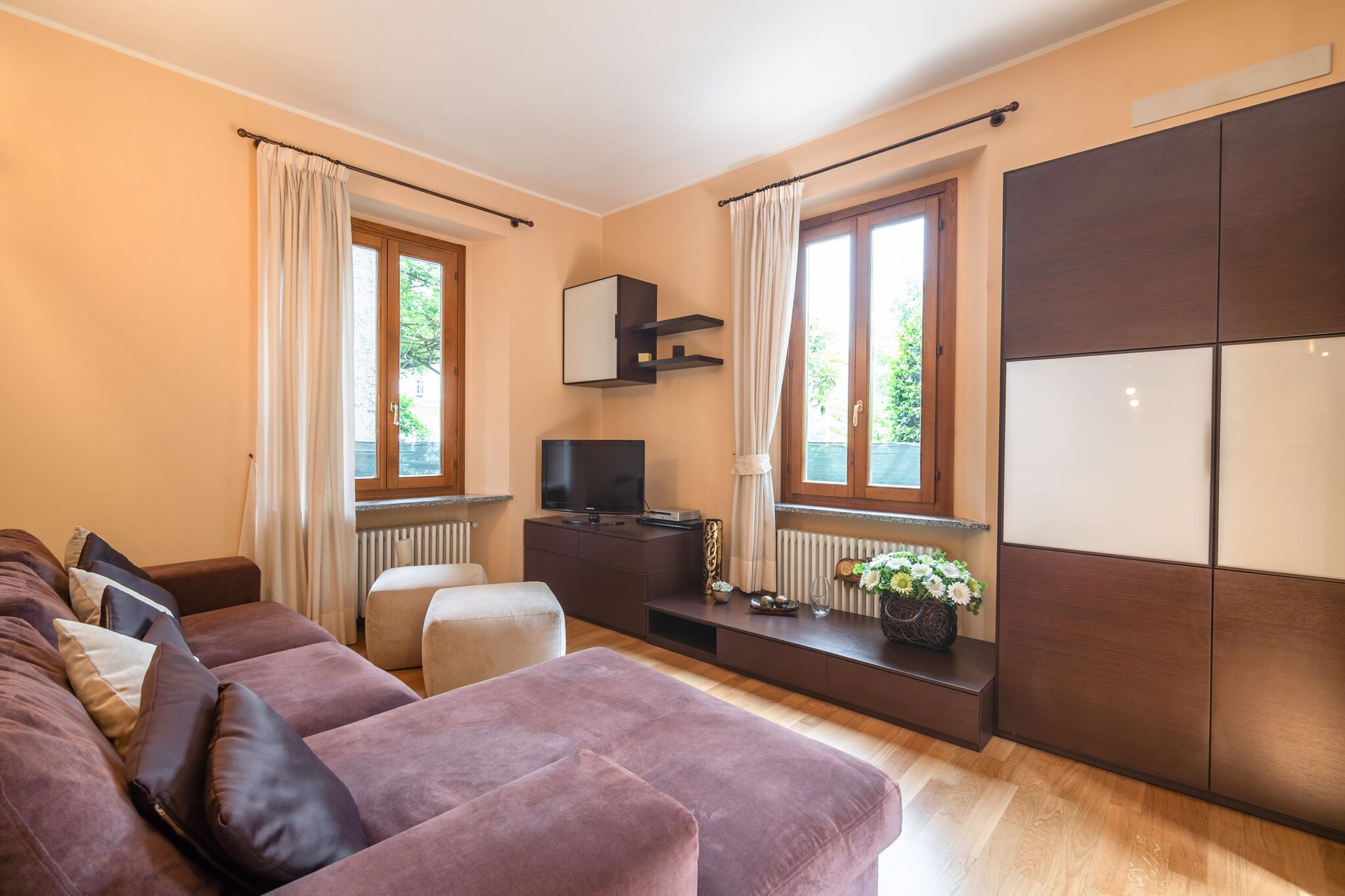 Ein modernes Wohnzimmer mit einer Couch, einem Fernseher und einem Stauraum.