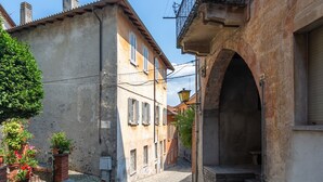 Une rue étroite, bordée de bâtiments des deux côtés, avec une arche en pierre et un petit banc.