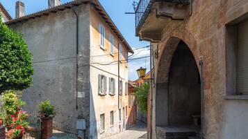 A narrow street with buildings on either side, featuring a stone archway and a small bench.