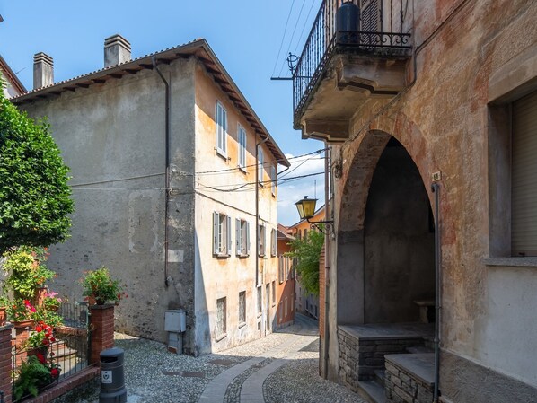 A narrow street with buildings on either side, featuring a stone archway and a small bench. - Appartamento in centro storico a Cannero Riviera (Cannero)
