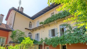 Un bâtiment à deux étages doté d’un balcon, d’une antenne visible et d’un jardin délimité par une clôture.