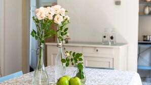 Une table ornée d’un arrangement floral dans des bouteilles en verre et d’une assiette de pommes vertes.