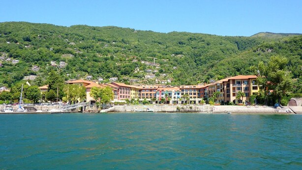 Un hôtel situé sur la côte, composé de plusieurs bâtiments, doté d’un port de plaisance et surplombant des collines verdoyantes.