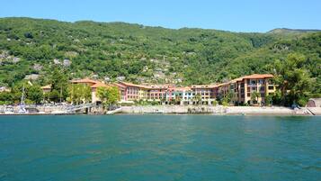 A coastal hotel with multiple buildings, a marina, and a backdrop of green hills.