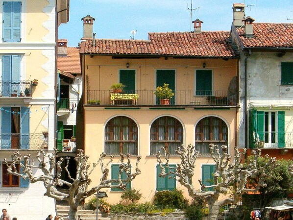 A building with a yellow facade, green shutters, and a tiled roof.