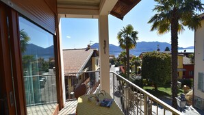 A balcony with a table, a view of a town, and a mountain in the background. - Spacious Retreat in Cannero (Cannero Riviera)