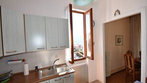 A kitchen with a window, a radiator, and a dining area with chairs. - Spacious Retreat in Cannero (Cannero Riviera)