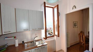 Eine Küche mit Fenster, Heizkörper und einem Essbereich mit Stühlen.