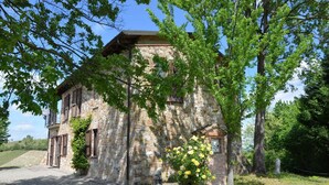 A stone building with a brick entrance, surrounded by trees and a clear sky.