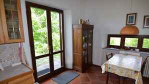 A kitchen with a dining table, wooden cabinets, and a window with a view of greenery.