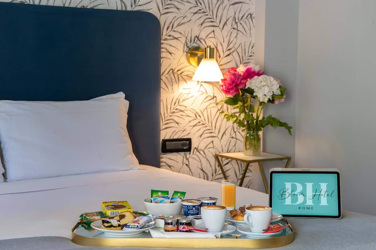 A neatly made breakfast tray with various food items and a glass of orange juice on a bed.