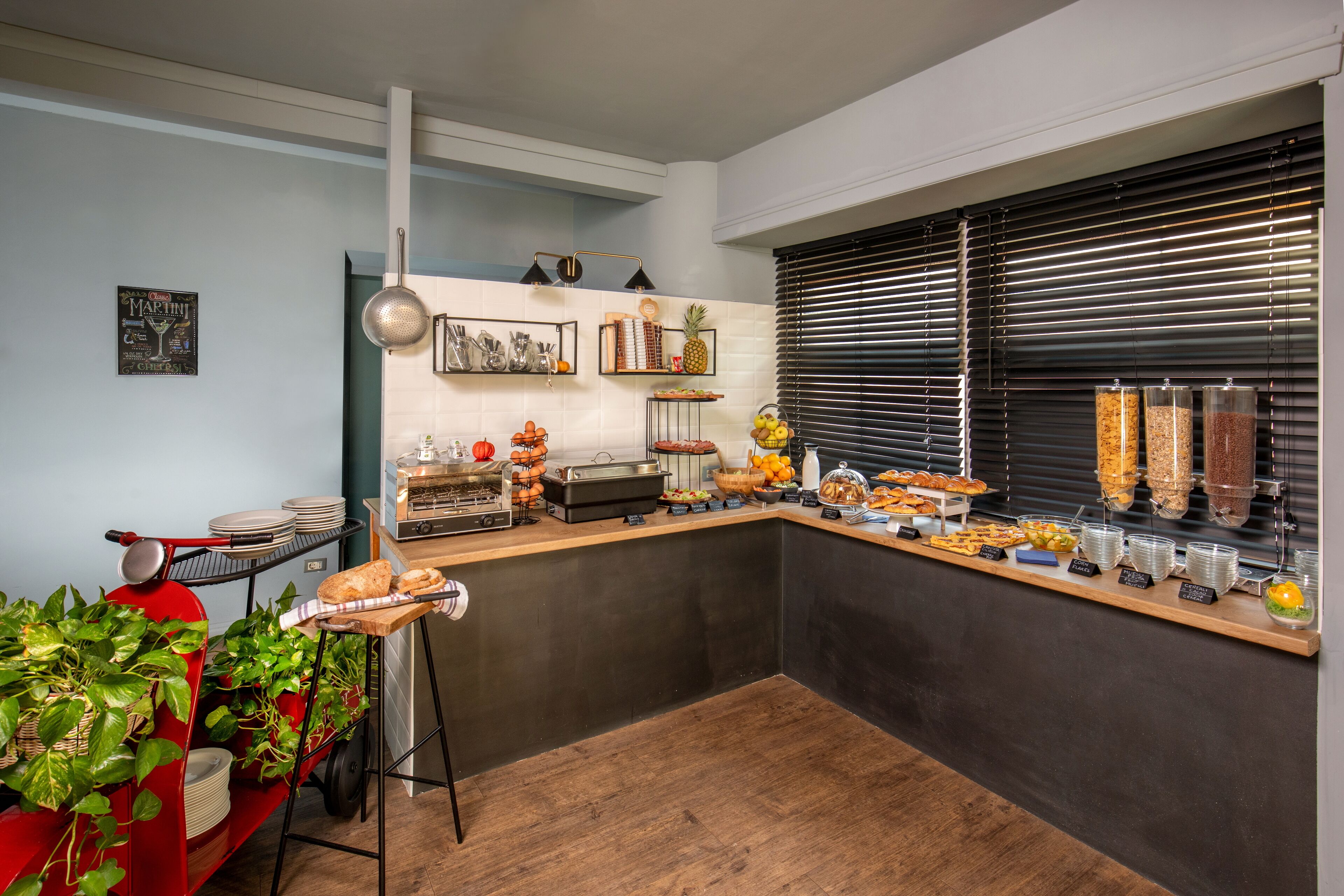 Montaje de bufé con diversos alimentos y un carrito rojo con plantas.