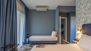 A hotel room with a bed, bedside table, lamp, and a view of the hallway.